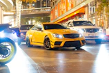 A golden sports car gleaming under city lights in downtown Montreal.