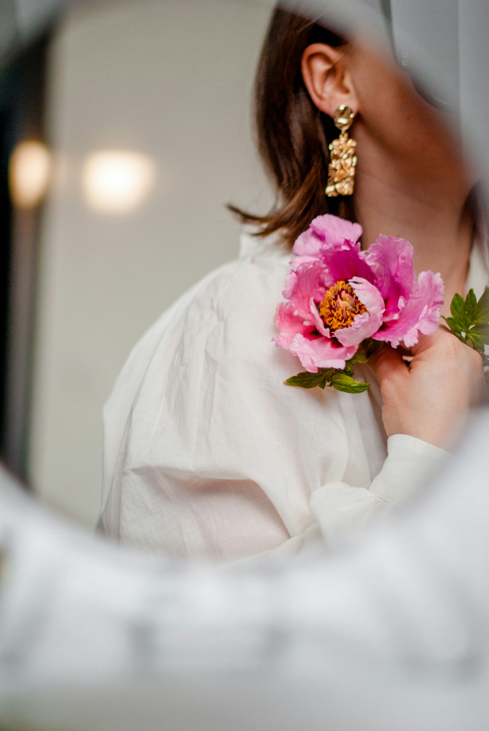 woman in white dress holding pink flower