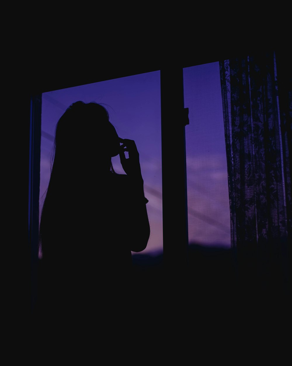 silhouette of woman standing near window during daytime