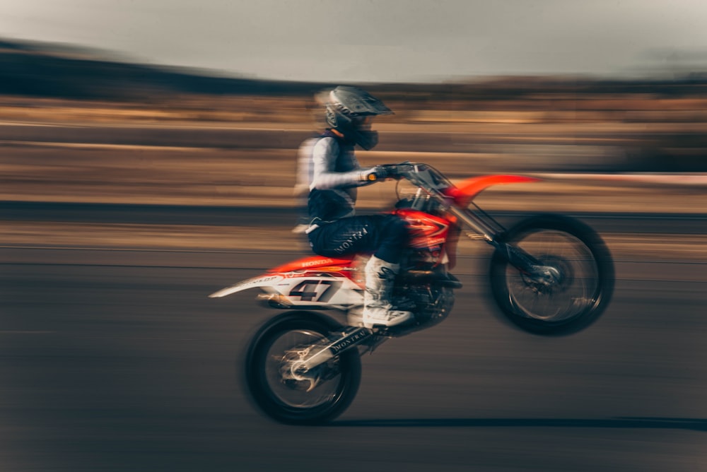 man in black and red motorcycle suit riding on red and black sports bike