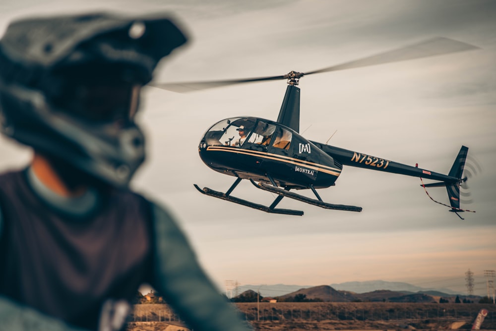 black and red helicopter flying over brown field during daytime