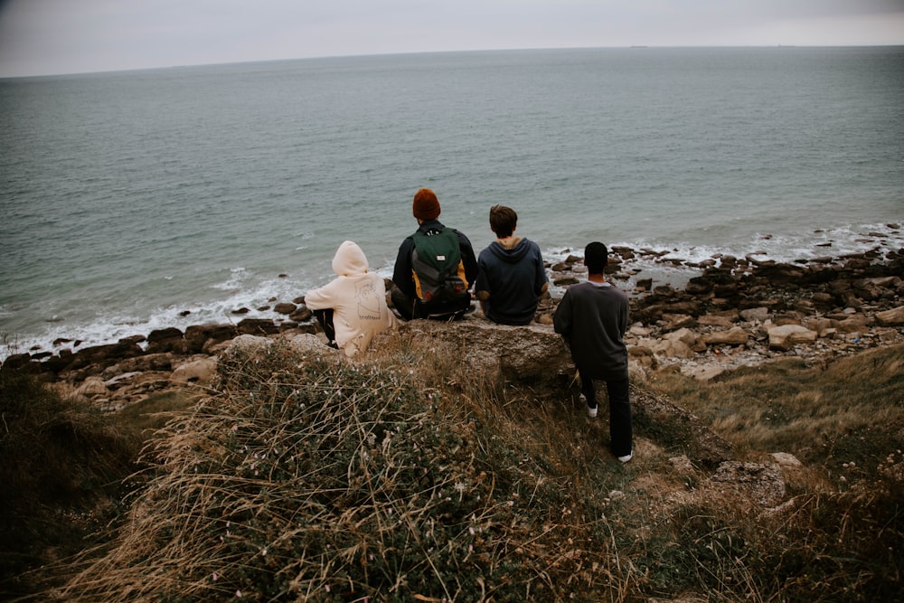 man and woman sitting on brown rock near body of water during daytime