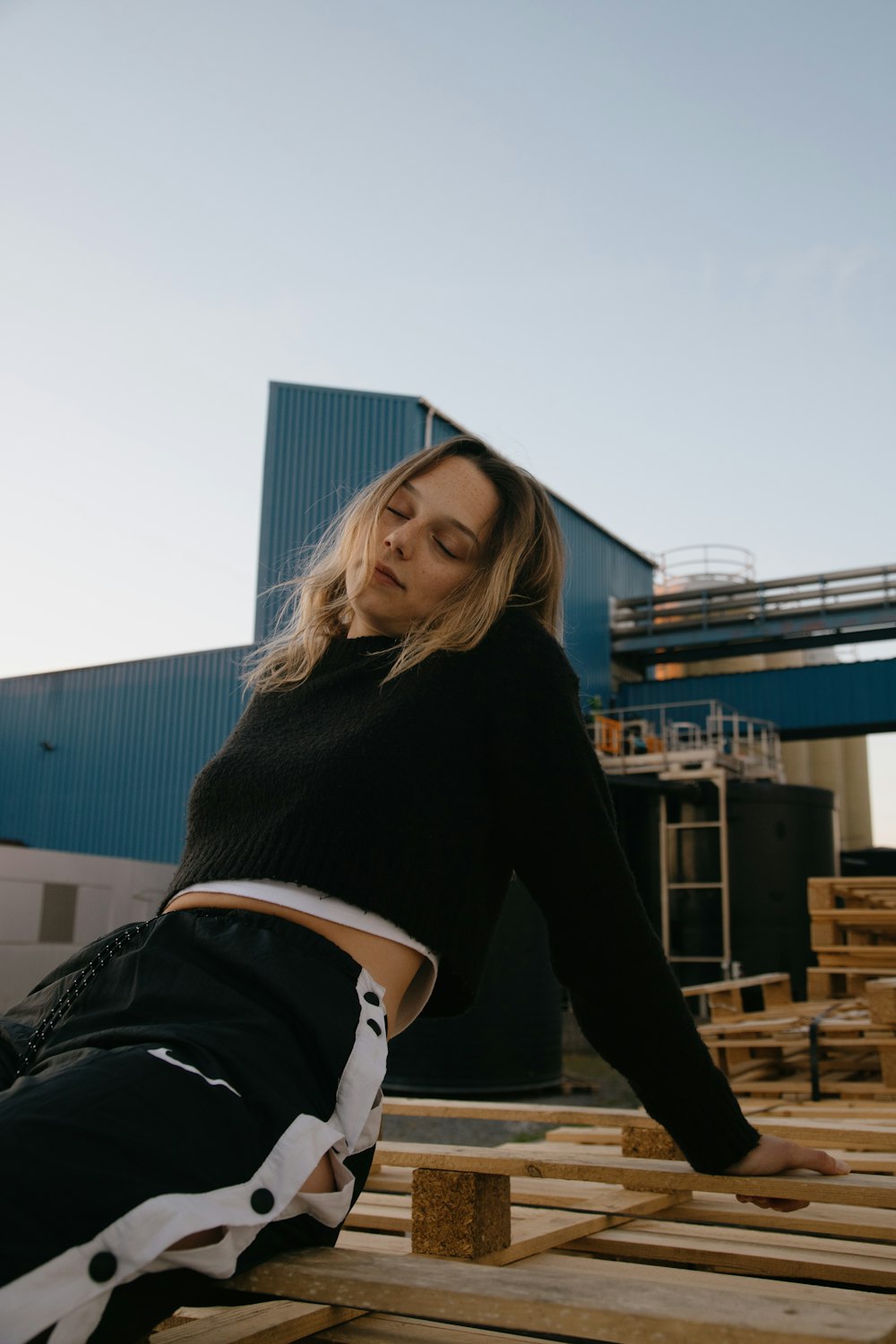 woman in black sweater and white shorts sitting on brown wooden bench during daytime