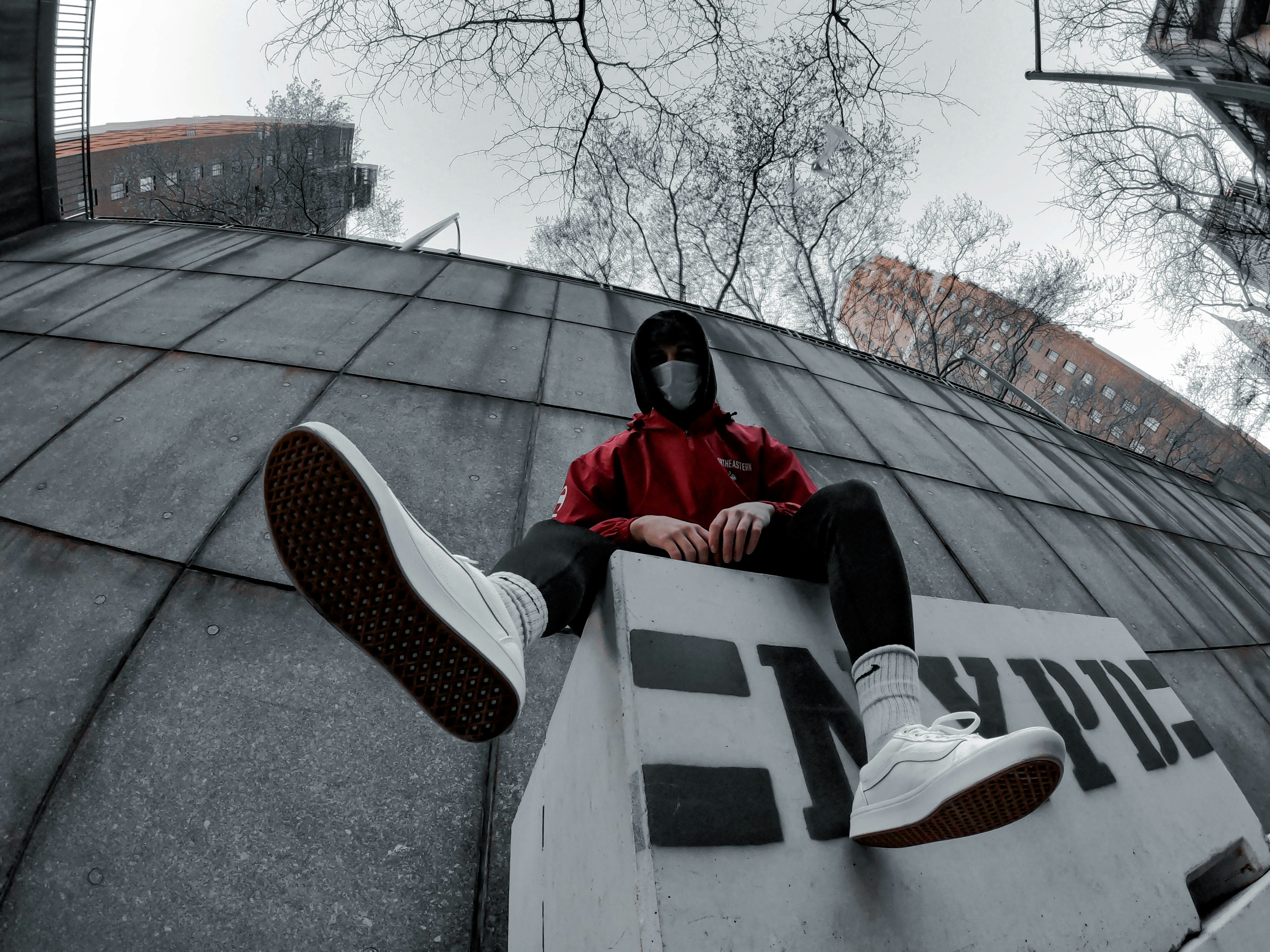 man in red jacket sitting on white concrete bench during daytime