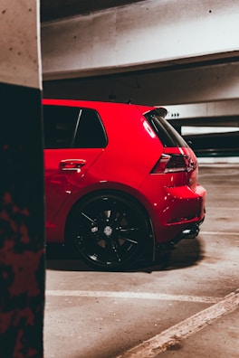 A bright red hatchback parked in front of the airport Al Massira terminal.