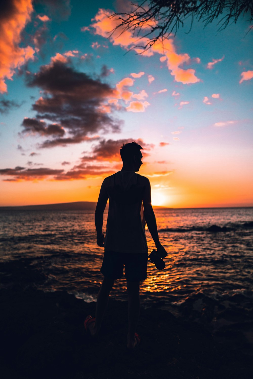 Silueta del hombre de pie en la playa durante la puesta del sol