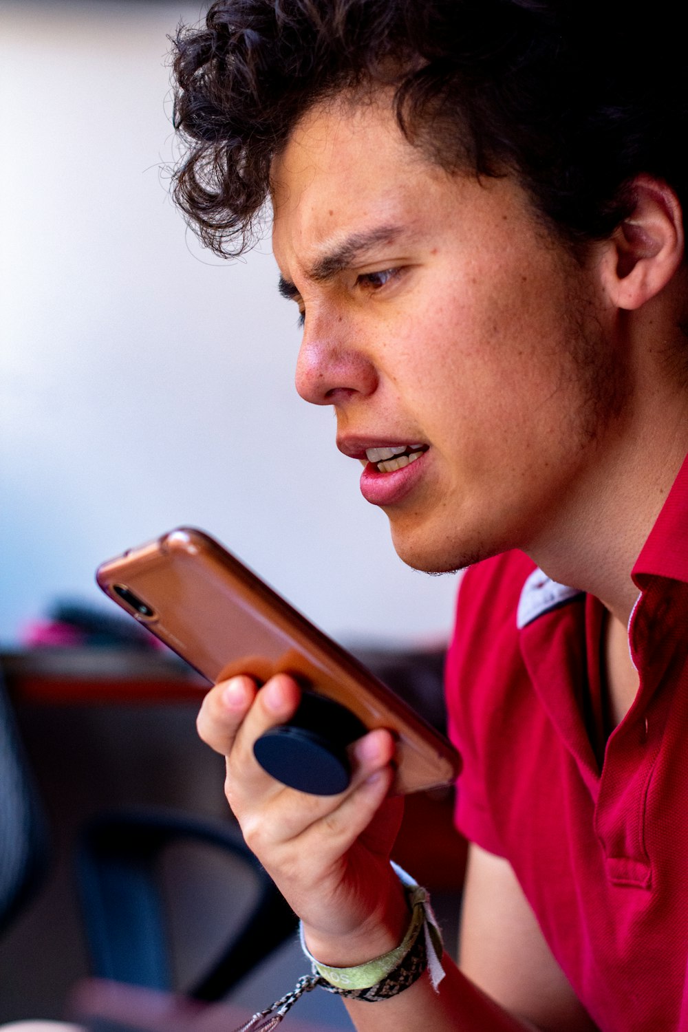 man in red polo shirt holding gold iphone 6