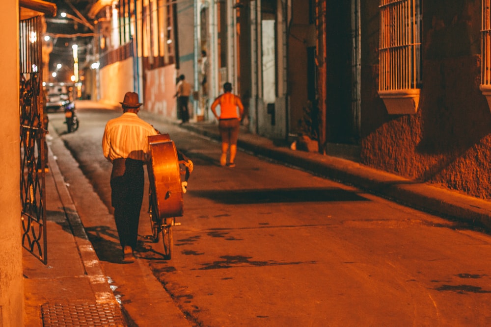 homem de camisa branca e calça preta andando na calçada durante o dia