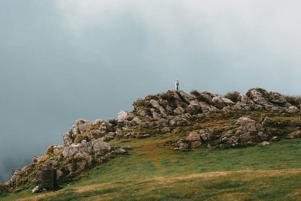 person standing on rock formation under white sky during daytime