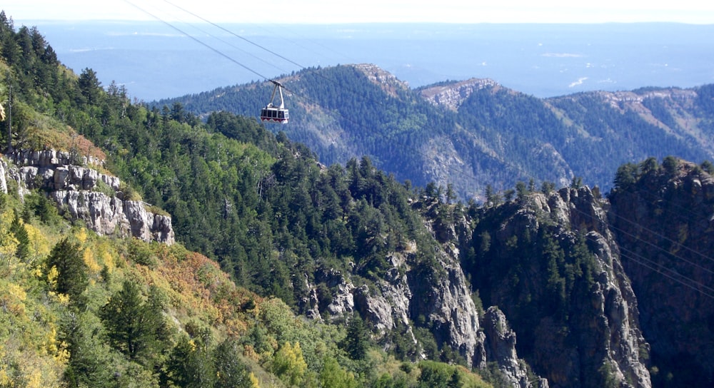 Funivia bianca sopra la montagna verde e marrone durante il giorno