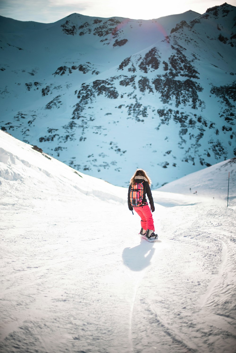 woman in black jacket and red pants standing on snow covered ground during daytime