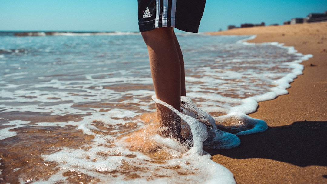 person in black shorts standing on beach during daytime