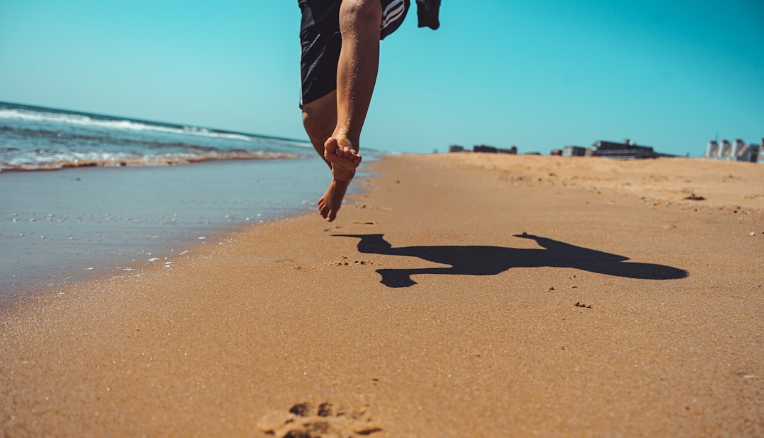 person in black shorts walking on beach during daytime