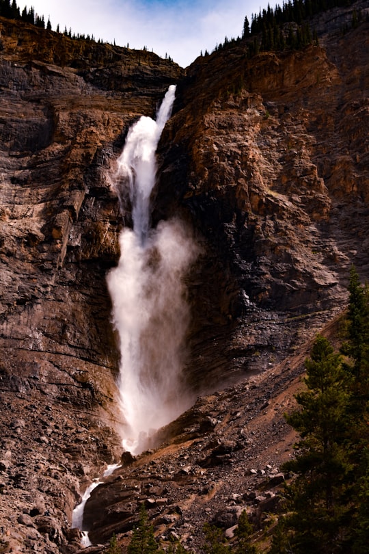 water falls on brown rocky mountain in Takakkaw Falls Canada