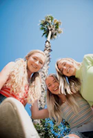 3 women smiling and standing under blue sky during daytime
