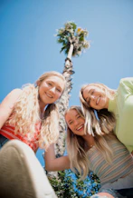 3 women smiling and standing under blue sky during daytime