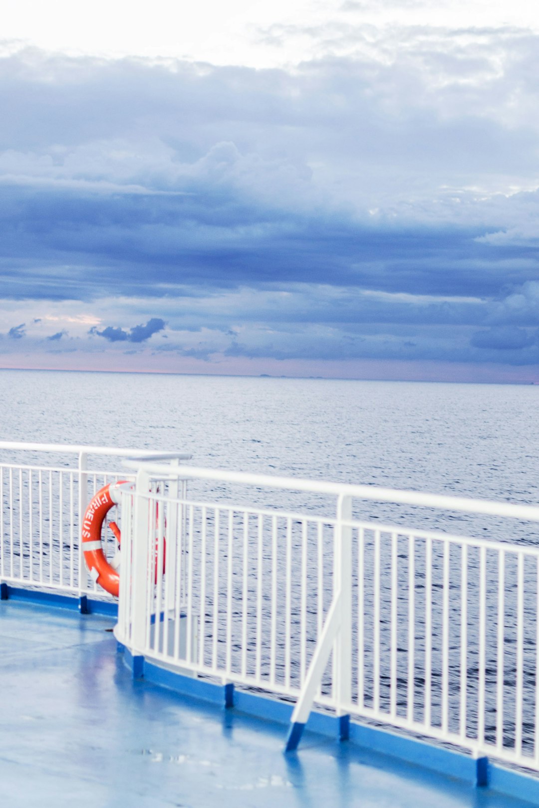 white metal railings on blue body of water under white clouds during daytime