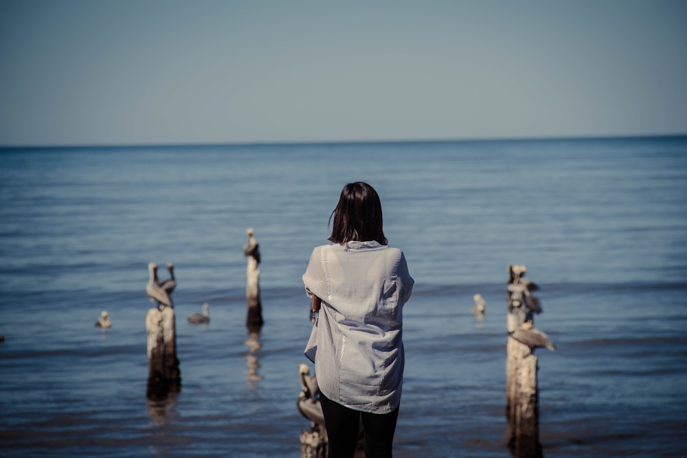 woman in white shirt and black pants standing on sea dock