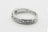 A silver ring with a row of seven small, sparkling diamonds embedded along its band. The interior of the band is inscribed with '14K'. The ring is simple yet elegant, showcasing a minimalist design.