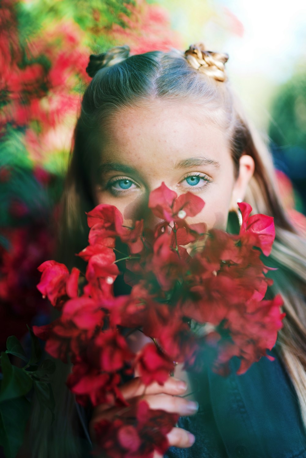 girl hiding behind red flowers