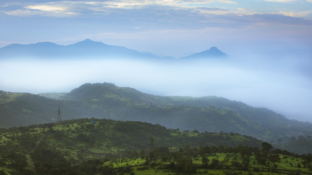 green trees and mountains under white clouds and blue sky during daytime