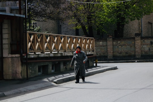 man in black jacket walking on sidewalk during daytime in Gori Georgia