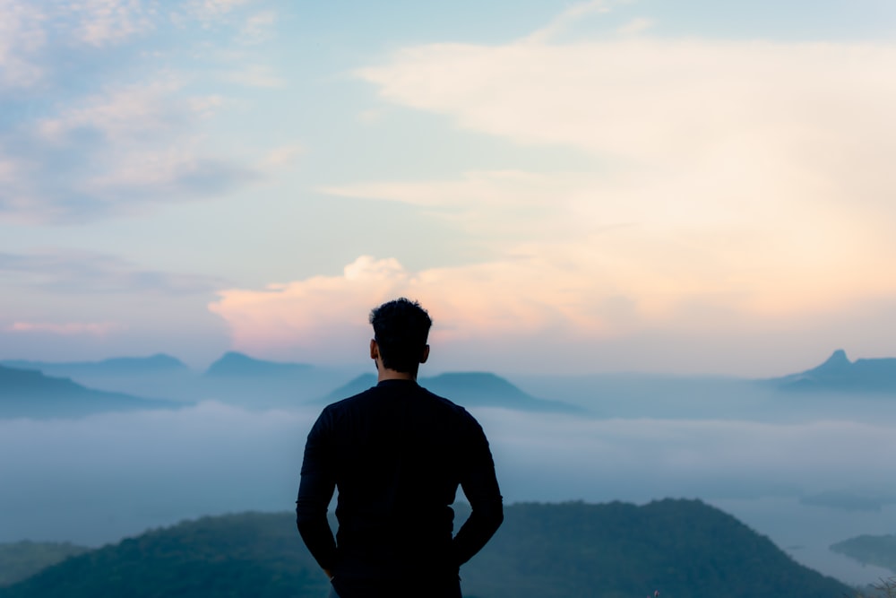 man in black long sleeve shirt standing on top of mountain during daytime