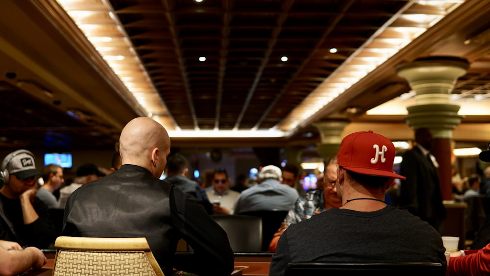 man in black crew neck shirt wearing red cap sitting on chair