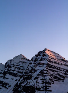 Snow-capped Himalayan peaks glowing under a clear blue sky at dawn.