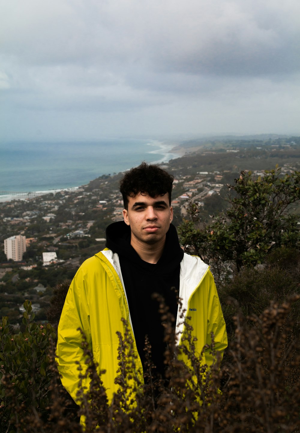 man in yellow jacket standing on top of mountain during daytime