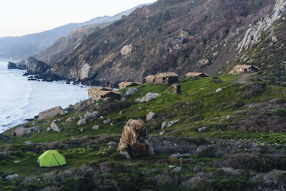 green dome tent on green grass field near body of water during daytime