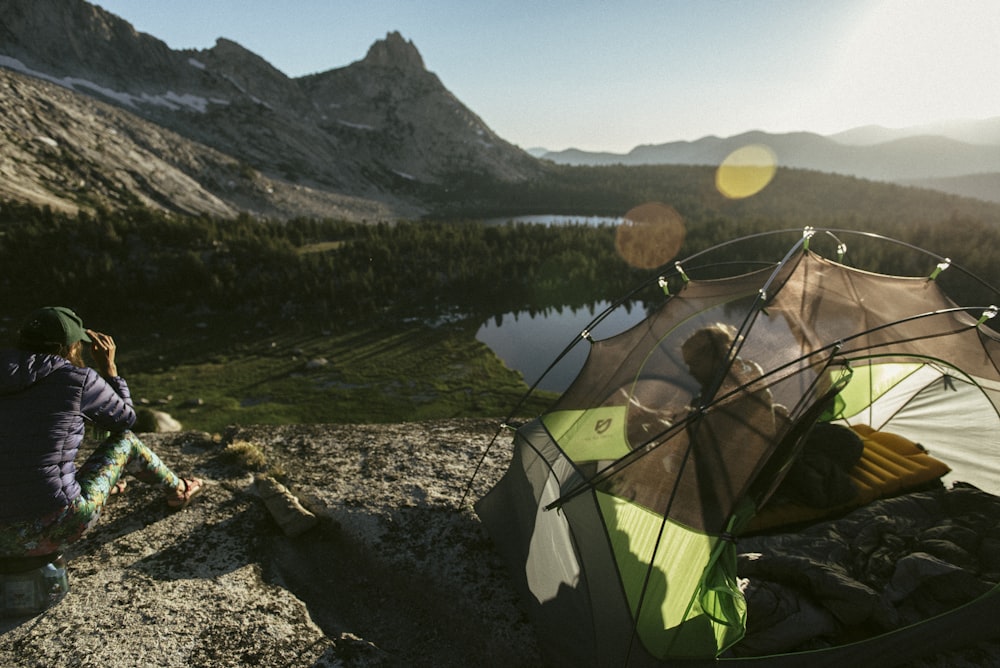 green tent near lake and mountains during daytime