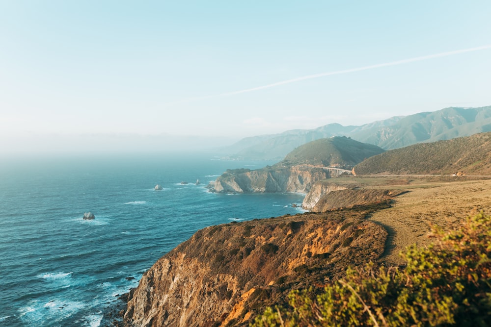 green and brown mountain beside sea during daytime