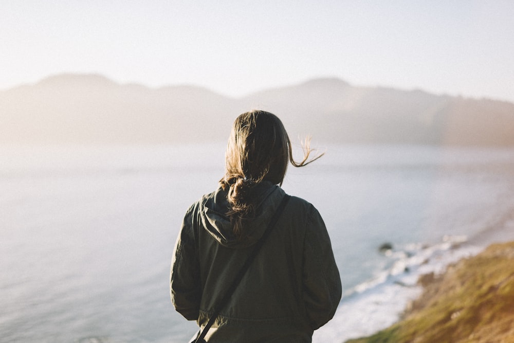 woman in black hoodie standing on rock formation during daytime