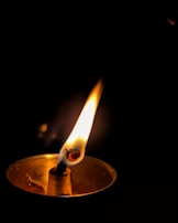 Close-up of an eye reflecting a flickering candle in darkness.