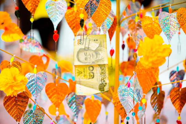 Colorful Thai baht notes spread out on a vibrant market stall surface.