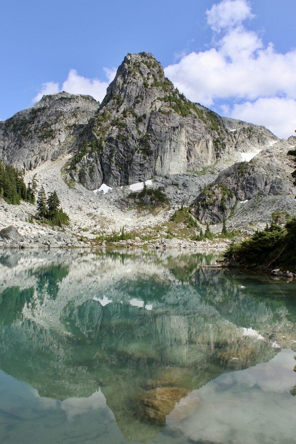 green lake near gray mountain during daytime