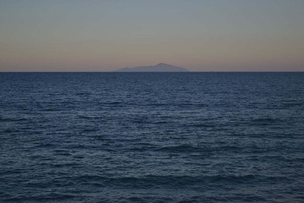 body of water near mountain during daytime