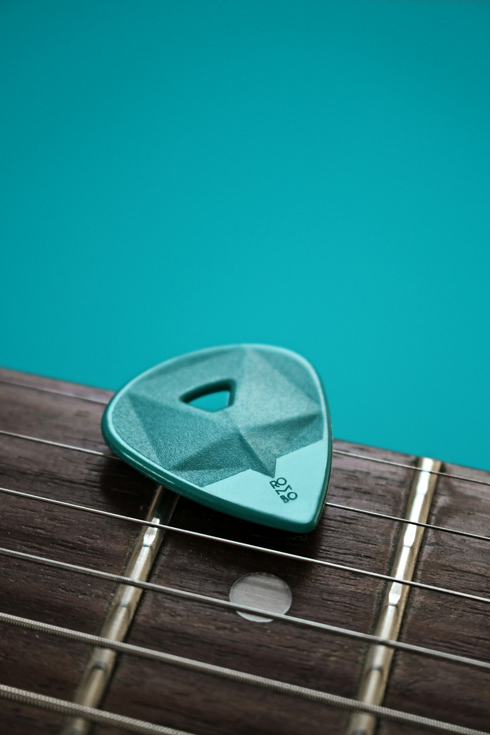 silver guitar pick on blue surface
