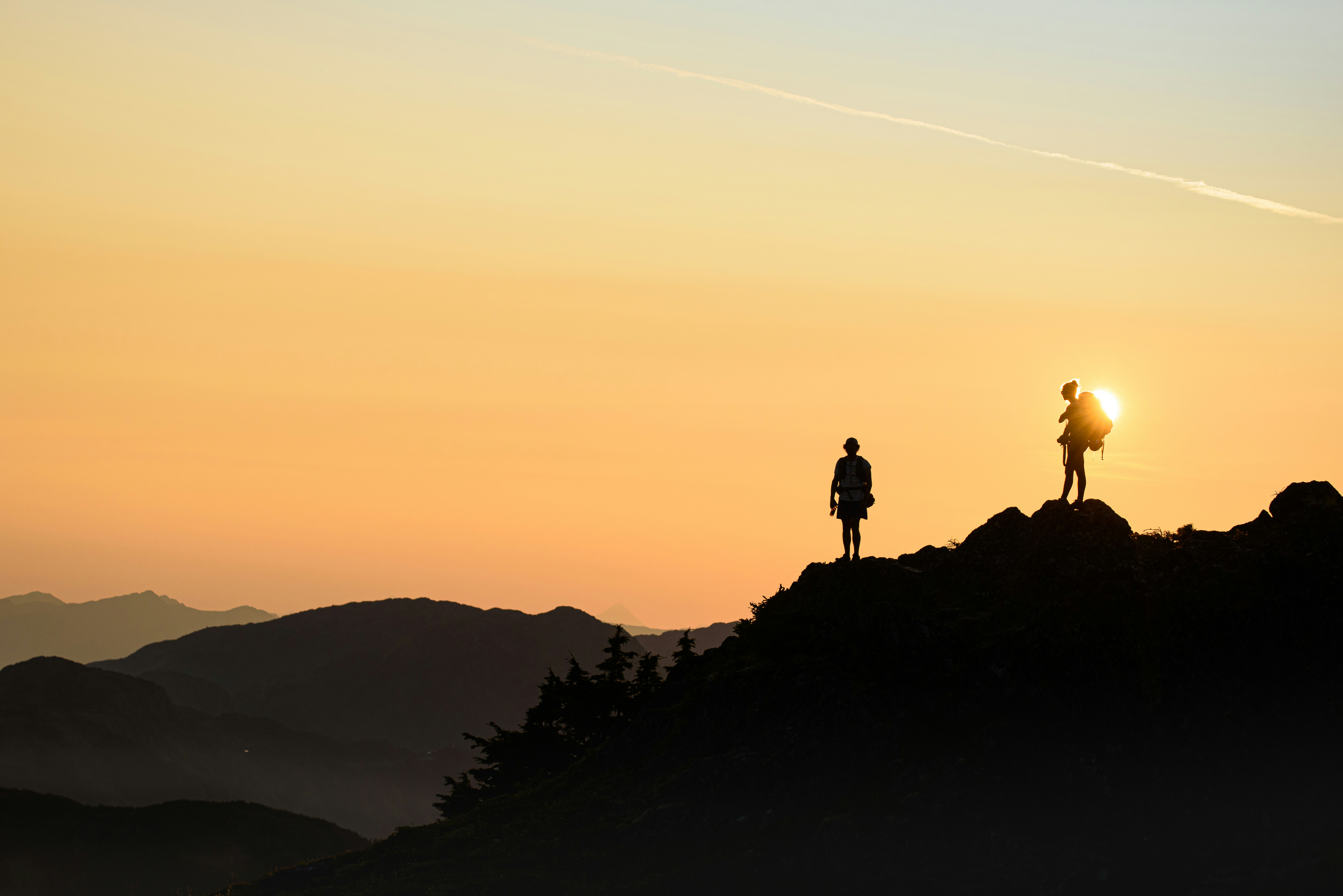 Une silhouette d'une femme debout au sommet d'une montagne au lever du soleil, représentant la résilience et la force.