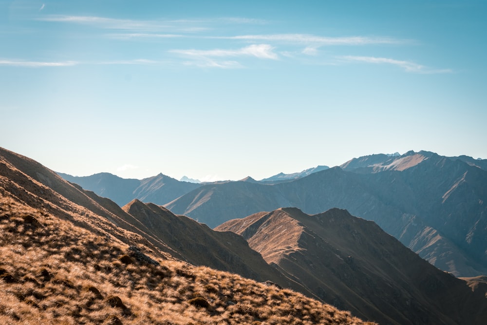 Montañas marrones y negras bajo nubes blancas y cielo azul durante el día