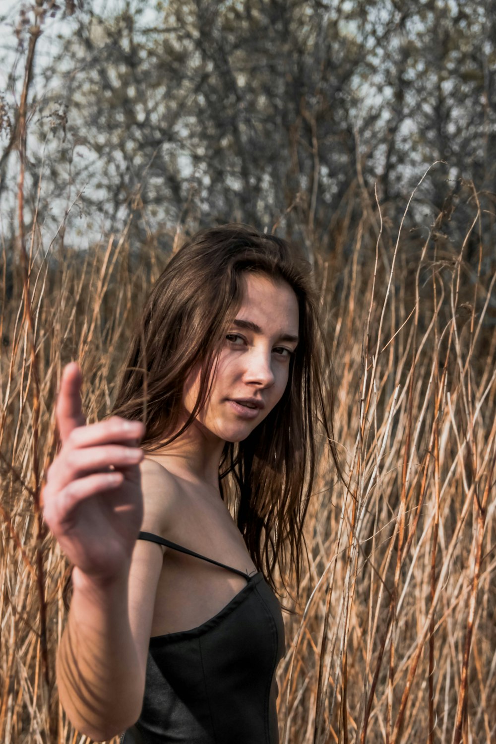 woman in black spaghetti strap top standing on brown grass field during daytime