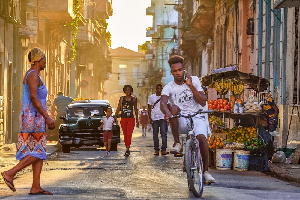 man in white crew neck t-shirt riding bicycle on street during daytime