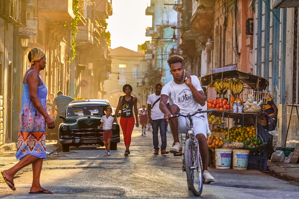 homme en blanc ras du cou t-shirt faire du vélo dans la rue pendant la journée