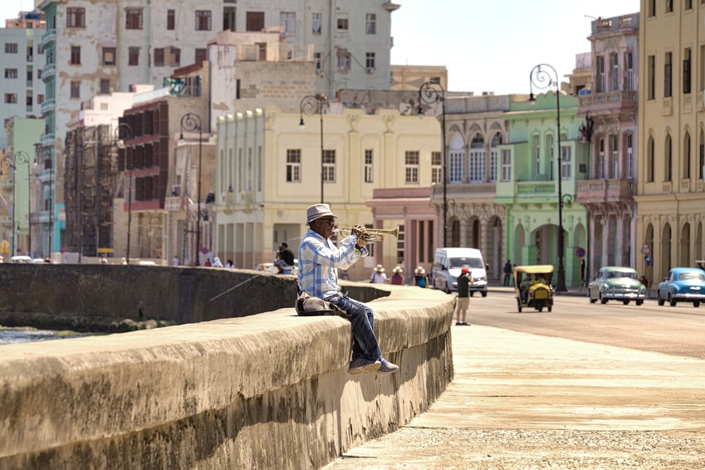 man in white shirt and gray pants sitting on concrete bench during daytime