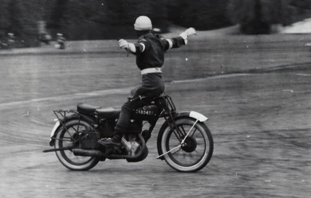 Foto in scala di grigi di un uomo in sella a una moto