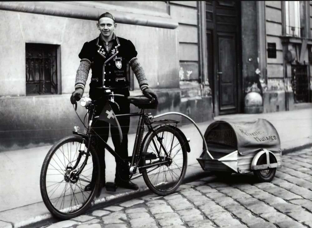 grayscale photo of woman in black jacket and pants standing beside bicycle