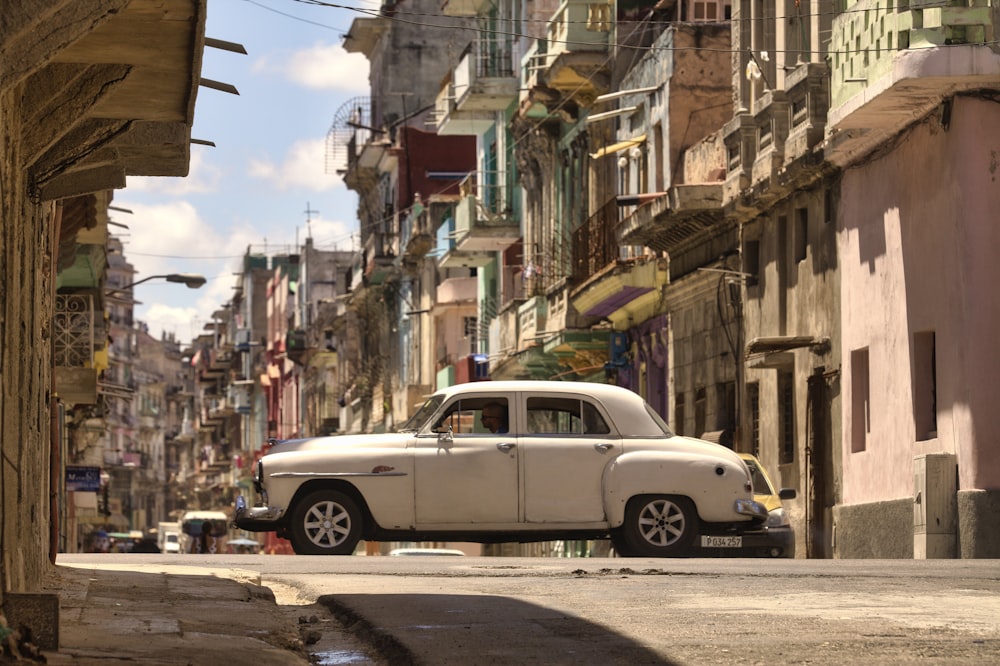 white sedan parked beside red and white concrete building during daytime