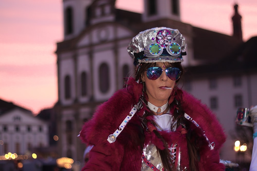 woman in purple fur coat wearing blue and green floral goggles