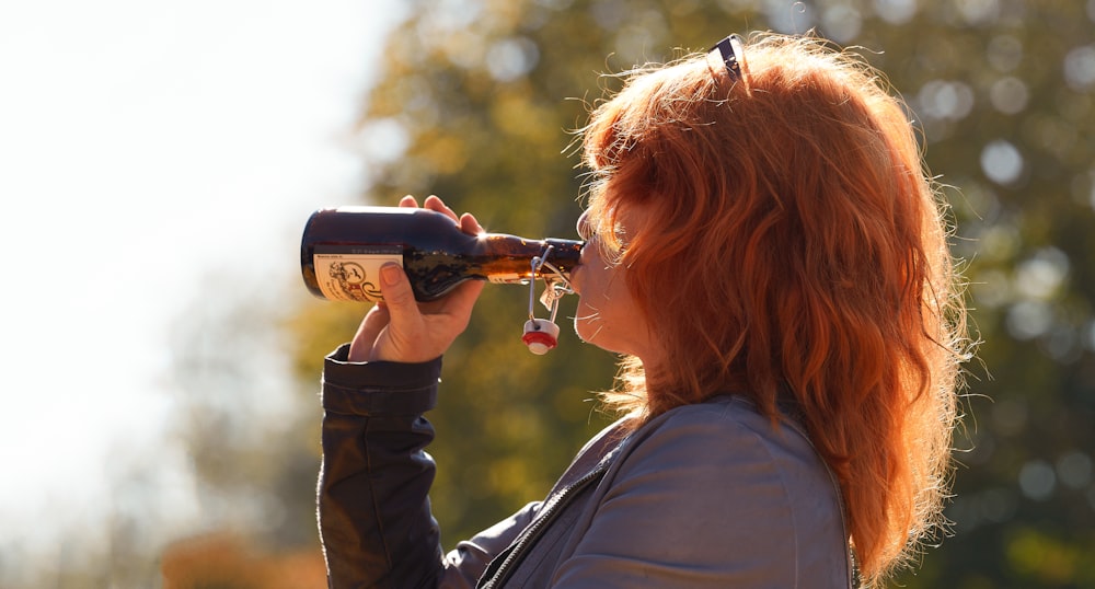 woman in black long sleeve shirt drinking from black ceramic mug during daytime